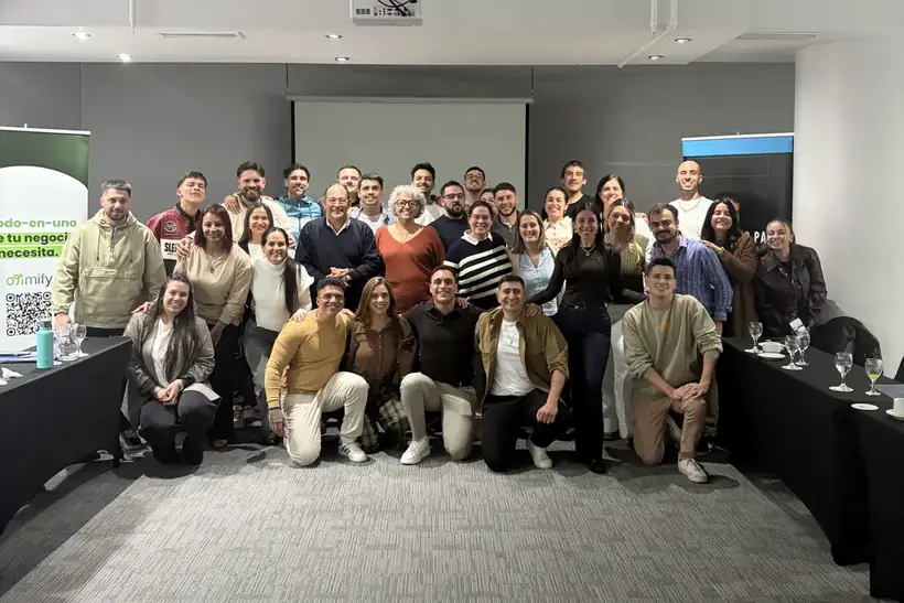Foto grupal de unas treinta personas al cierre del bootcamp, con un banner de Otimify a un costado.